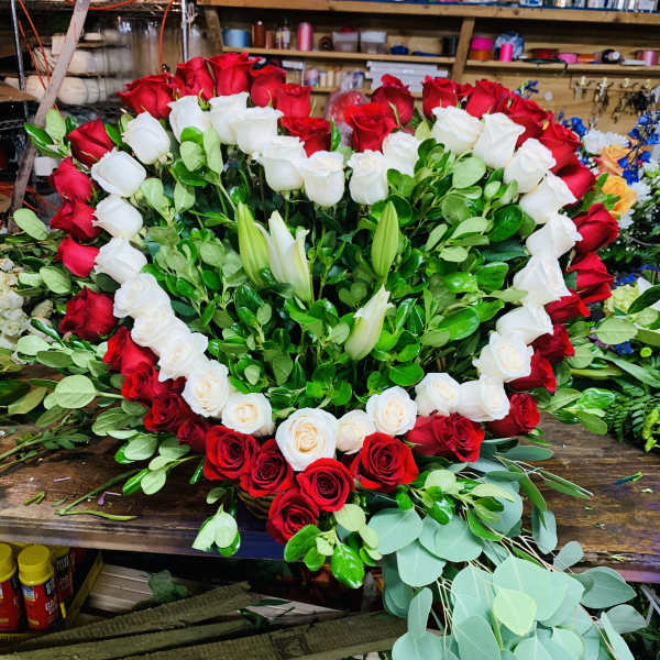 Heart-shaped red and white rose arrangement with lilies and greenery