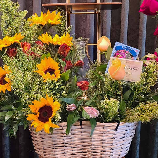 Basket arrangement with sunflowers, roses, and mixed greenery