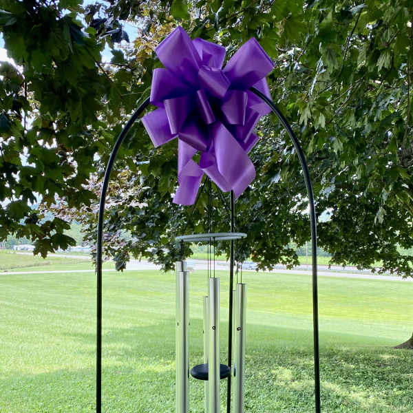 Purple ribbon bow on a black metal wind chime stand outdoors