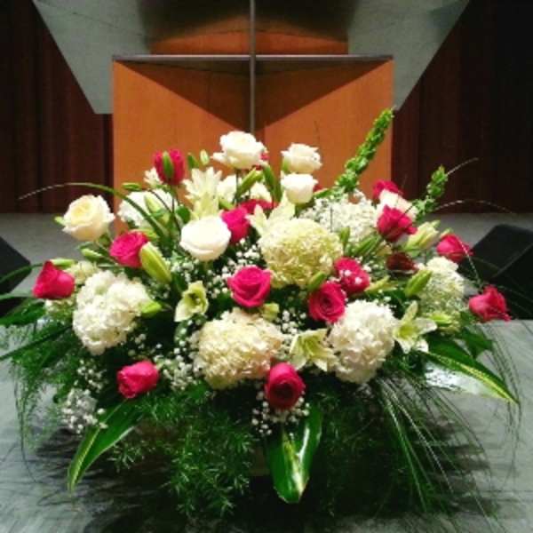 Large altar-style arrangement of red and white flowers with lilies and hydrangeas.
