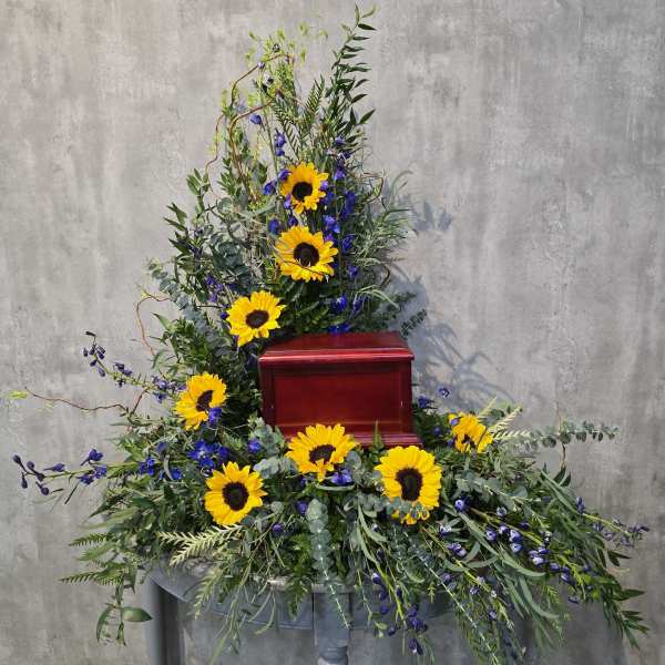 Sunflower funeral spray around a red urn on a pedestal