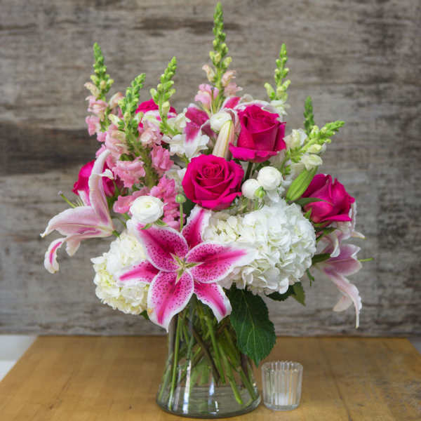 Pink roses and lilies arranged in a clear glass vase