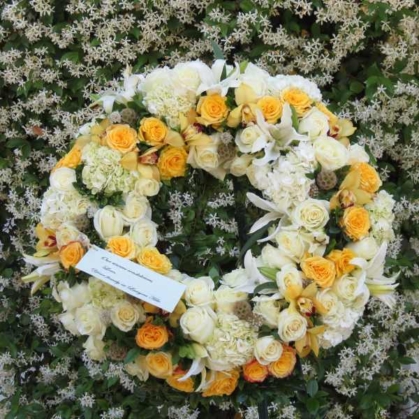 Large floral wreath of white and yellow blooms on a flower-covered backdrop