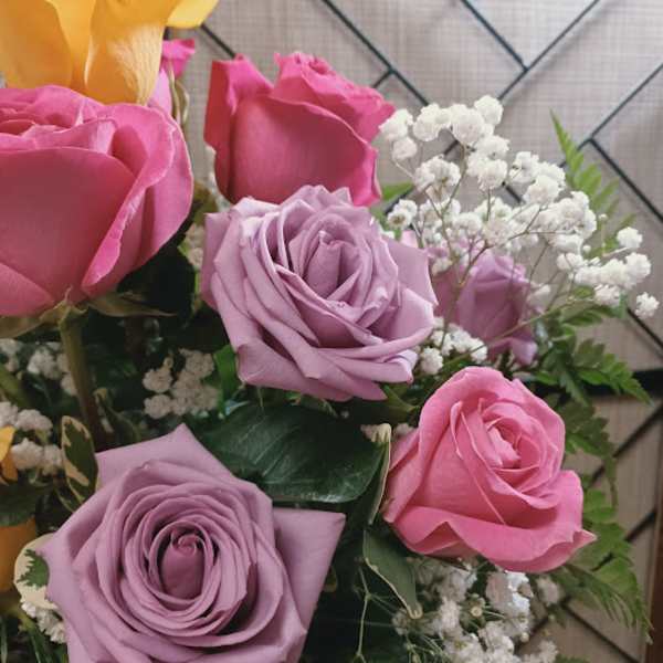 Bouquet of pink and lavender roses with white baby's breath and a yellow calla lily