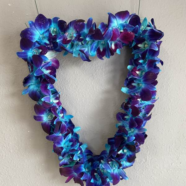 Heart-shaped floral wreath of blue and purple orchids on a wall