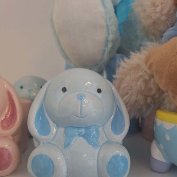 Blue ceramic bunny figurine with a bow sits on a shelf