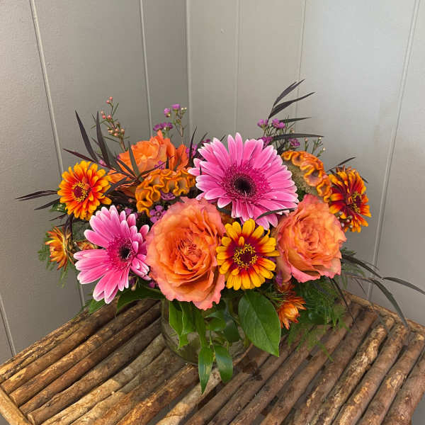 Bright mixed bouquet with pink gerberas and orange roses in a glass vase