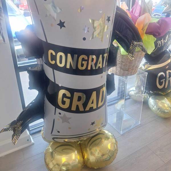 Graduation-themed balloon display shaped like a diploma with gold balloons at the base