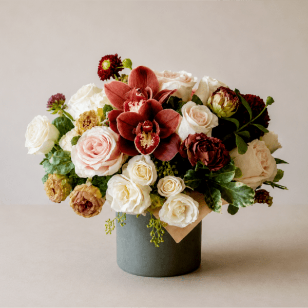 Bouquet of roses and burgundy orchids in a gray vase