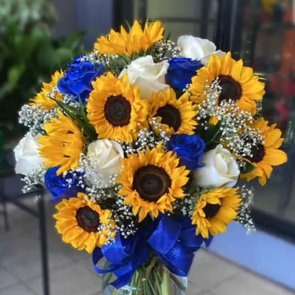 Bouquet of sunflowers and blue and white roses in a glass vase