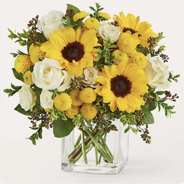 Yellow sunflowers and white roses in a clear glass vase