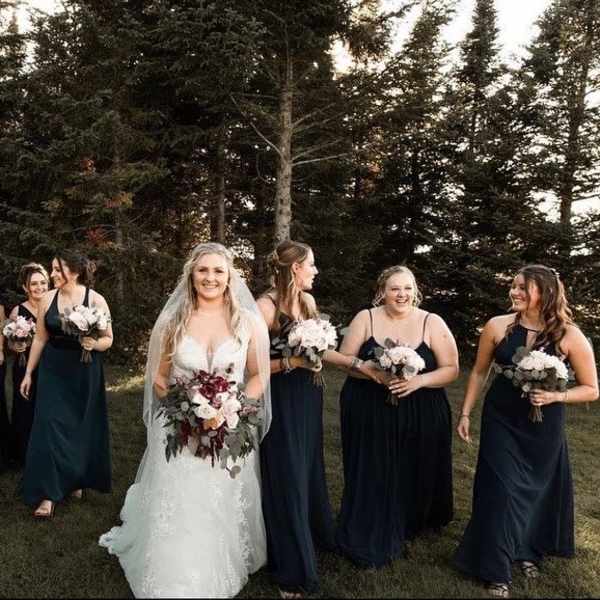 Bride and bridesmaids holding white and blush bouquets outdoors