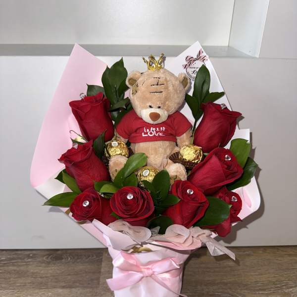 Bouquet of red roses with a teddy bear and chocolates in pink wrapping