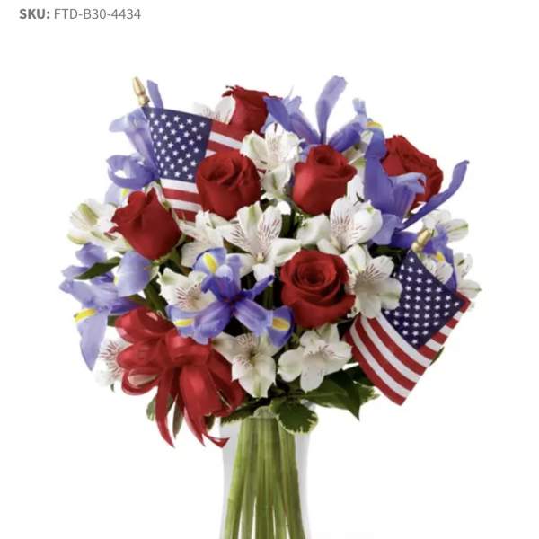 Bouquet of red roses and white flowers with small American flags in a glass vase