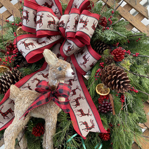 Christmas wreath with plaid ribbon, pinecones, and straw deer ornaments