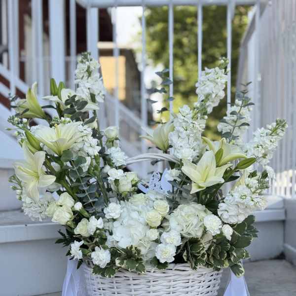 White floral basket arrangement with lilies, roses, and ribbon