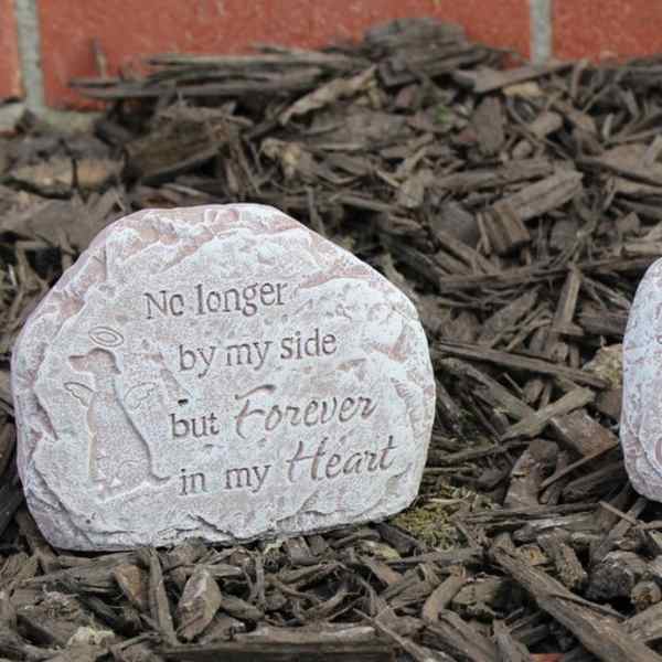 Two memorial stones with angel designs and engraved text in mulch