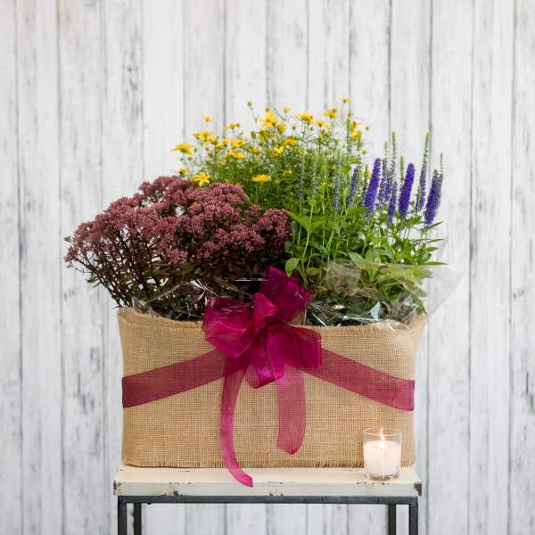 Mixed flowers in a burlap-wrapped basket with a pink ribbon and candle