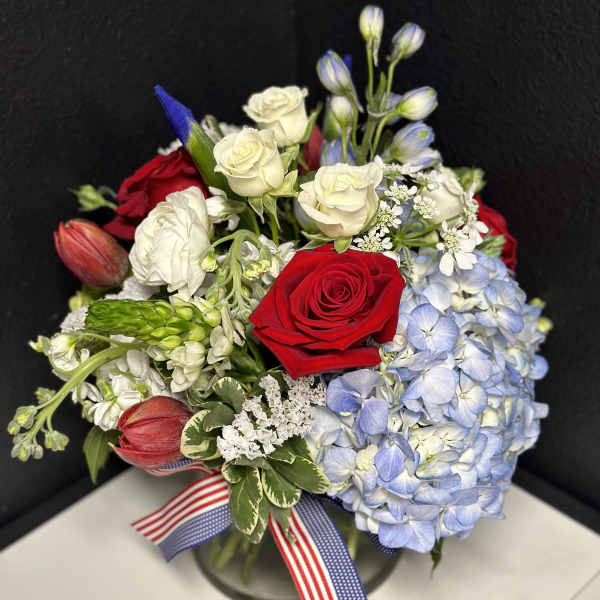 Bouquet of red and white roses with blue hydrangea in a glass vase