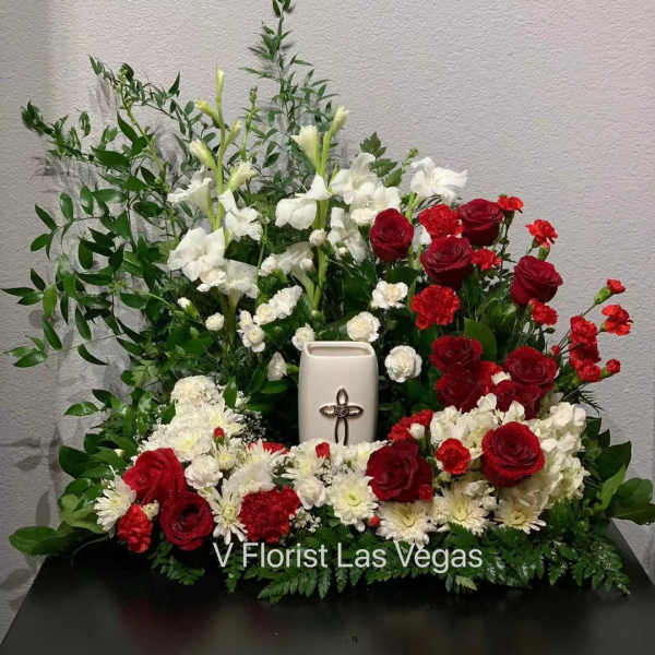 Red and white floral arrangement with a white urn and cross centerpiece