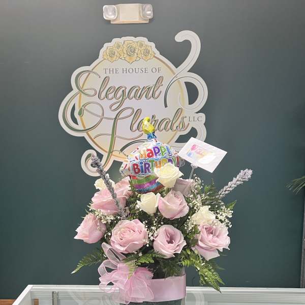 Pink and white rose arrangement in a glass vase with a birthday balloon