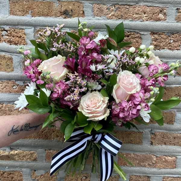 Hand-tied bouquet of pale pink roses and pink mixed flowers with a striped ribbon