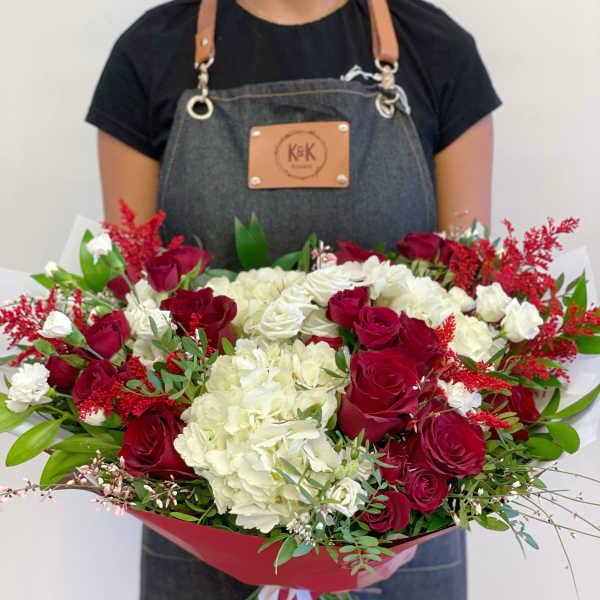 Large bouquet of red roses and white hydrangeas wrapped in red paper