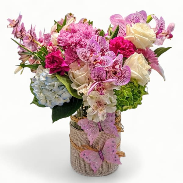 Pink and white mixed flower arrangement in a burlap-wrapped glass vase with pink butterfly accents