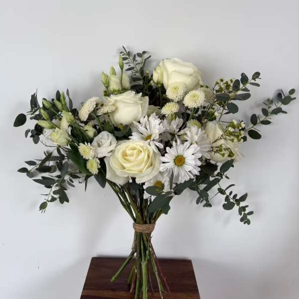 Bouquet of white roses and daisies with eucalyptus in a tied hand wrap