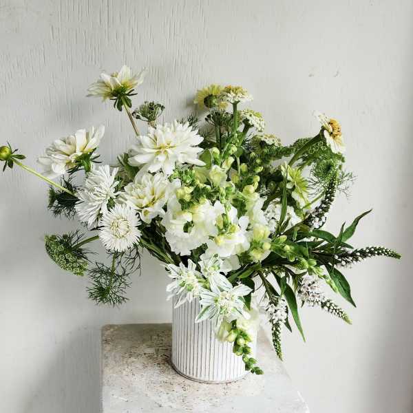 White floral arrangement in a ribbed white vase