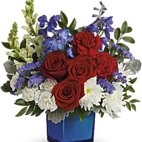 Red roses, white daisies, and blue flowers in a blue glass vase