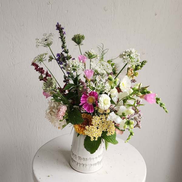 Mixed bouquet in a white ceramic vase with pink, white, and purple flowers