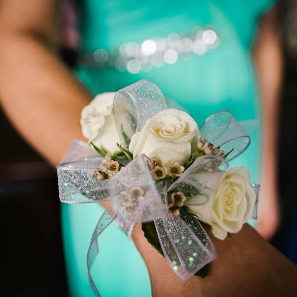 White rose corsage with silver ribbon on a wrist