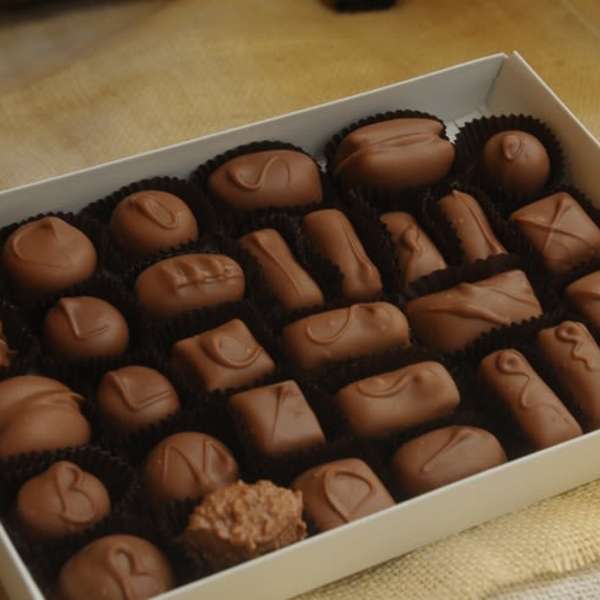 Box of assorted chocolate candies in paper cups
