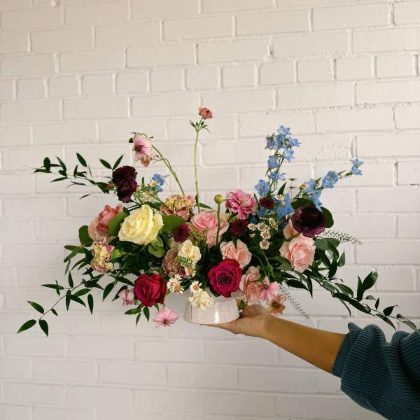 Mixed bouquet in a white vase with pink, blue, and cream flowers