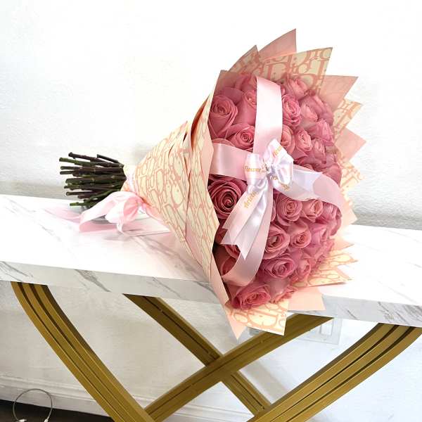 Pink rose bouquet wrapped in peach paper with a satin ribbon