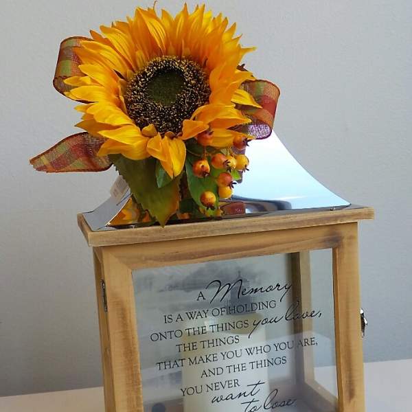 Sunflower arrangement on a wooden memorial box with a candle inside