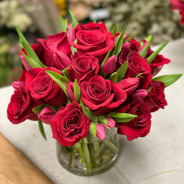 Red roses and pink tulips arranged in a clear glass vase