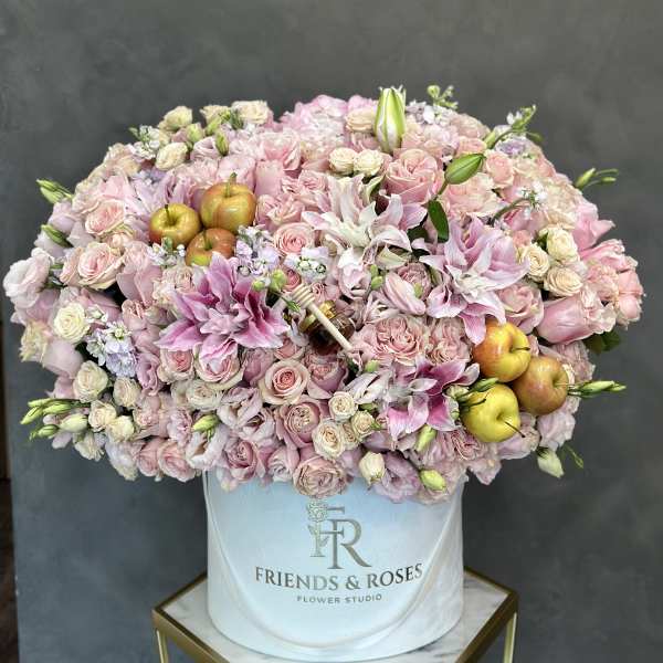 Large pink rose and lily arrangement in a white hat box with apples