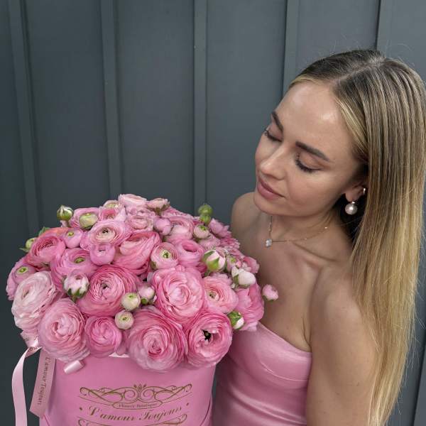 Woman holding a large pink box of pink ranunculus flowers