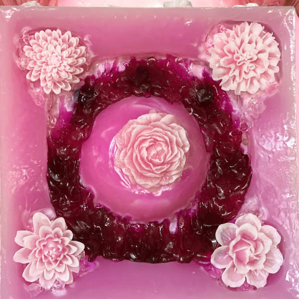 Pink floral cake with layered blossoms and a central rose