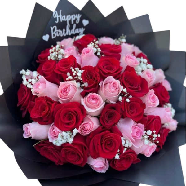 Bouquet of red and pink roses wrapped in black paper with a Happy Birthday topper