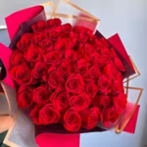 Large bouquet of red roses wrapped in pink and burgundy paper