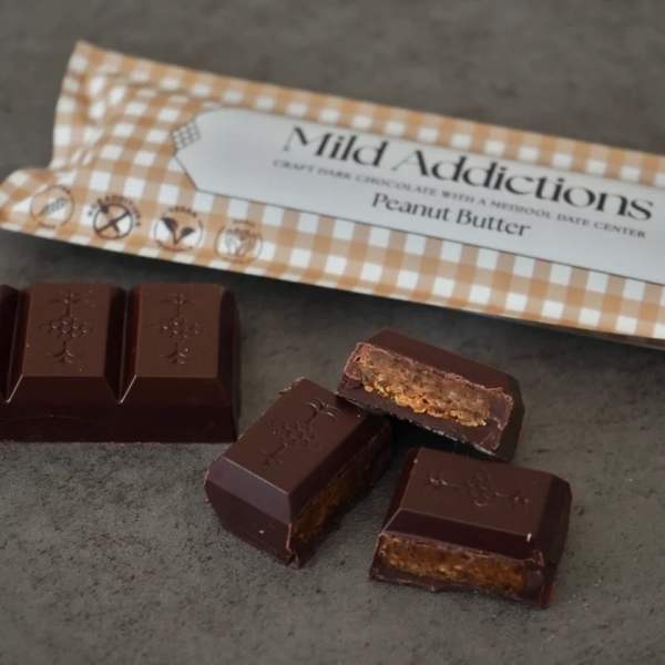 Unwrapped dark chocolate pieces with peanut butter filling beside branded wrapper.