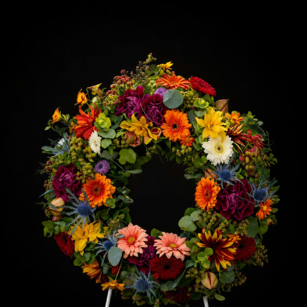 Colorful floral wreath on a white easel against a black background