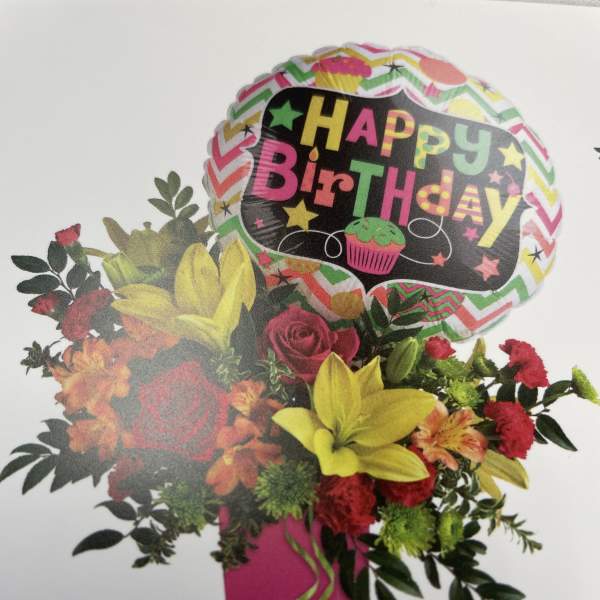 Birthday bouquet with roses, lilies, and a balloon in a pink vase