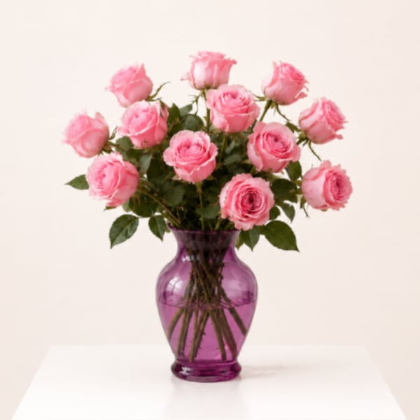 Pink roses arranged in a purple glass vase