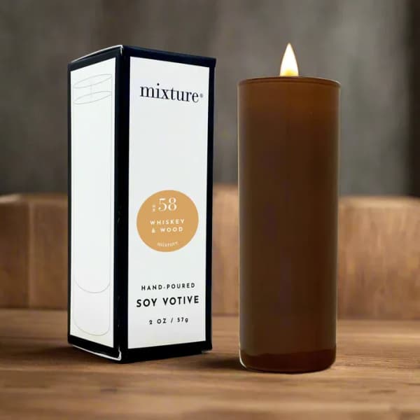 Brown votive candle beside its box on a wooden surface