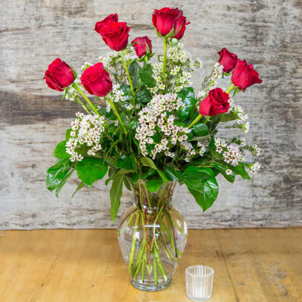Red roses and white filler flowers in a clear glass vase
