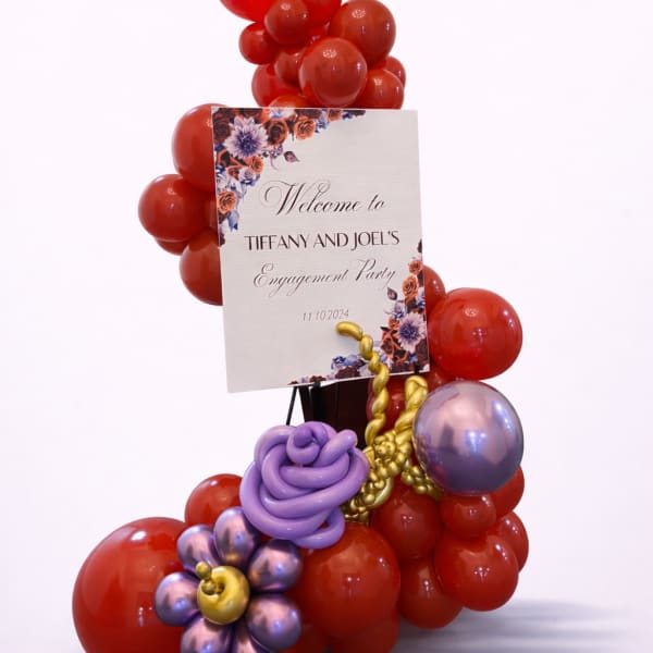 Red and purple balloon display with an engagement party sign